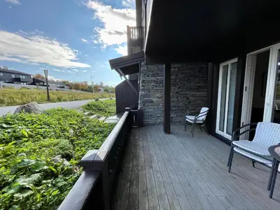 a deck with two chairs and a table on a house at Cozy 2-Bedroom Retreat In The Heart Of Nature in Beitostøl