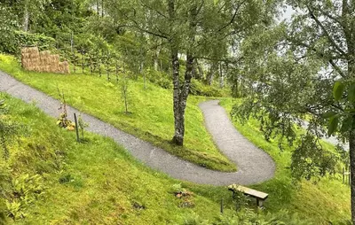 a winding path in a park with a bench at Beautiful Home In Vassenden in Vassenden
