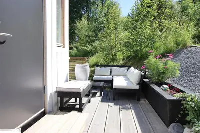 a porch with a couch and two chairs and a table at Skarnsundet apartment in Venneshamn