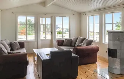 a living room with couches and a table and windows at 3 Bedroom Nice Home In Kvenvær in Kvenvær