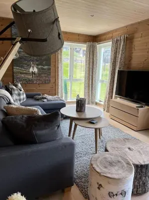a living room with a blue couch and a tv at ChaletMons, stor trivelig leilighet i Myrkdalen in Vossestrand