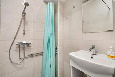 a bathroom with a shower curtain and a sink at BUDGETEL- Kong Oscarsgate 48 in Bergen