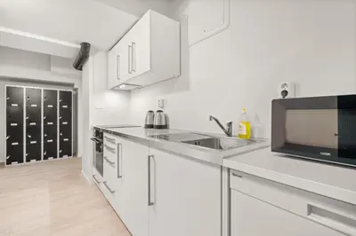 a white kitchen with a sink and a microwave at BUDGETEL- Kong Oscarsgate 48 in Bergen