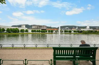 a man sitting on a bench in front of a lake at One of a kind in Bergen I 7 Bedrooms I 15 Guests! in Bergen