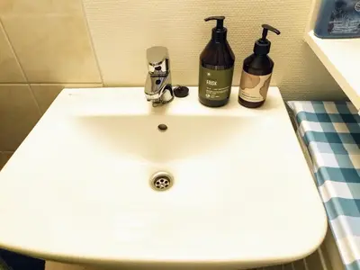 a white bathroom sink with two bottles on it at Cosy apartment near city center in Bergen