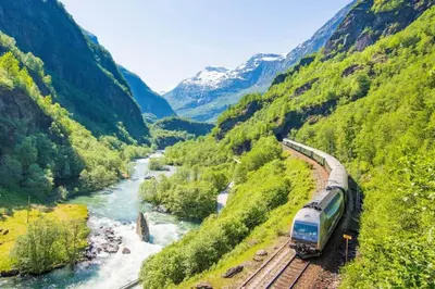 a train traveling down the tracks next to a river at Feriehus i Lærdal in Mjeldo