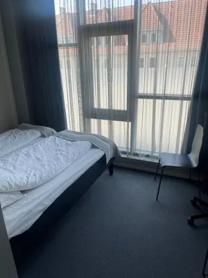 a bedroom with a bed and a chair next to a window at Lilleby Apartment in Trondheim