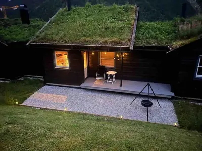 a small house with a grass roof with a table and a chair at Rekkehus i Myrkdalen in Helgatun
