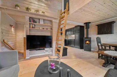 a living room with a large television and a wooden wall at Rekkehus i Myrkdalen in Helgatun