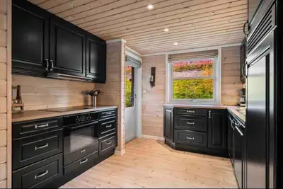 a kitchen with black cabinets and a window at Rekkehus i Myrkdalen in Helgatun