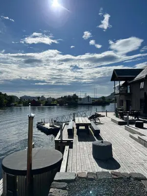 a dock with a table and benches on the water at Amundøya Penthouse in Kristiansund