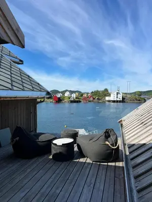 a dock with chairs and a table on a body of water at Amundøya Penthouse in Kristiansund