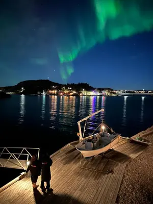 two people standing on a dock next to a boat at Amundøya Penthouse in Kristiansund