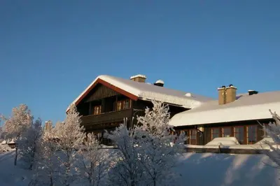 a building covered in snow with trees in front of it at 2-Bedroom Apartment With Balcony & Fireplace! in Beitostøl