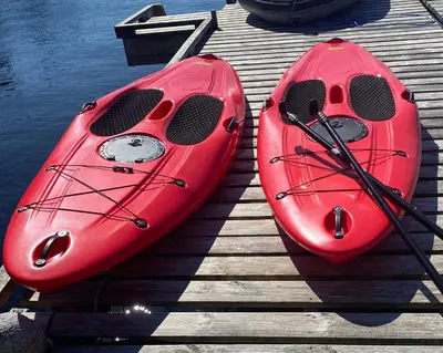 two red kayaks sitting on a dock next to the water at Nydelig villa ved sjøen med oppvarmet basseng in Bergen