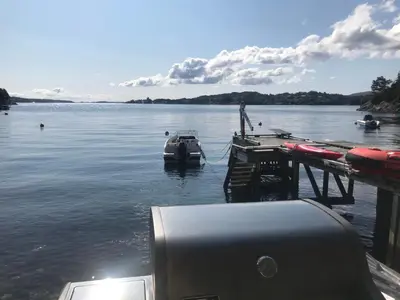 a boat is docked at a dock on a lake at Nydelig villa ved sjøen med oppvarmet basseng in Bergen
