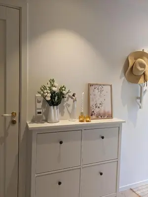 a dresser with flowers and a hat on top of it at Meget hjemmekoseligISentraltINyoppusset leilighet in Bergen