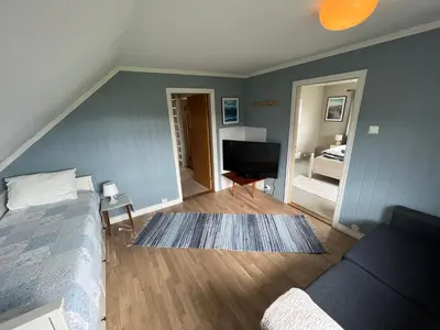 a bedroom with a bed and a living room at Sjønært feriehus, båt tilgjengelig for leie in Ålesund