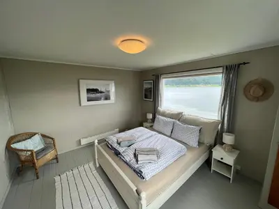 a small bedroom with a bed and a window at Sjønært feriehus, båt tilgjengelig for leie in Ålesund