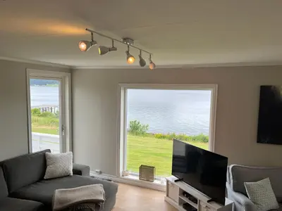 a living room with a couch and a large window at Sjønært feriehus, båt tilgjengelig for leie in Ålesund
