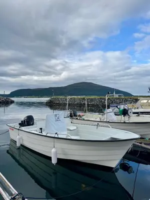 a white boat is docked in the water at Sjønært feriehus, båt tilgjengelig for leie in Ålesund