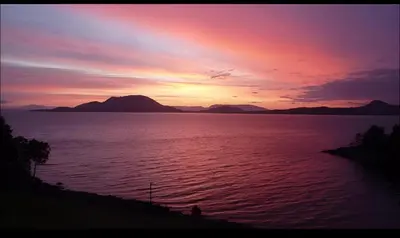 a sunset over a large body of water at Fjord house with a private bay, boats and sauna! in Etnesjøen
