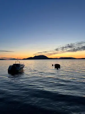 a boat sitting in the water at sunset at Fjord house with a private bay, boats and sauna! in Etnesjøen
