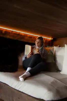 a woman sitting on a bed reading a book at GapaLux in Levanger