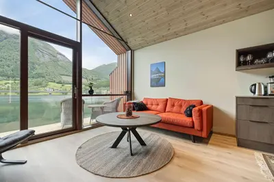 a living room with an orange couch and a table at Rorbu in Sykkylven