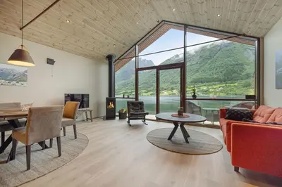 a living room with a large window and a table at Rorbu in Sykkylven