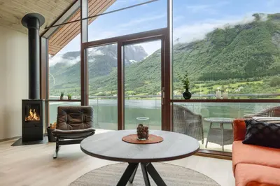 a living room with a table and a large window at Rorbu in Sykkylven