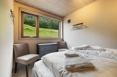 a bedroom with a bed and a chair and a window at Rorbu in Sykkylven
