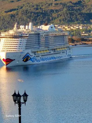 a cruise ship in the water next to a street light at Duzy apartament w centrum Ålesund in Ålesund