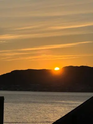 a sunset over the water with mountains in the background at Ålesund sentrum apartment in Ålesund