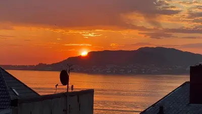a sunset over a body of water with the sun setting at Ålesund sentrum apartment in Ålesund