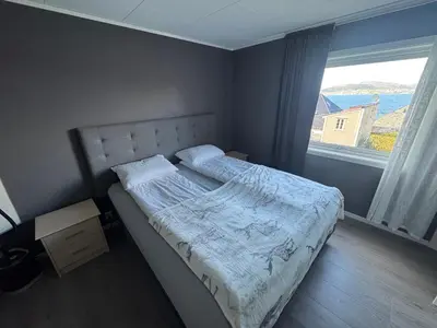 a bed in a bedroom with a large window at Ålesund sentrum apartment in Ålesund