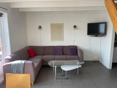 a living room with a couch and a tv at Seaside apartment with balcony A1 in Nautnes