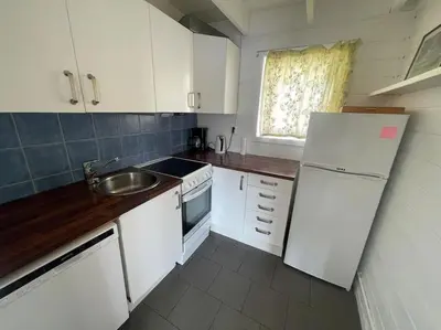 a kitchen with a white refrigerator and a sink at Seaside apartment with balcony A1 in Nautnes