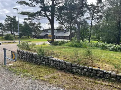 a rock retaining wall next to a road at Alværa Misionssenter Sommerhotel in Lavik