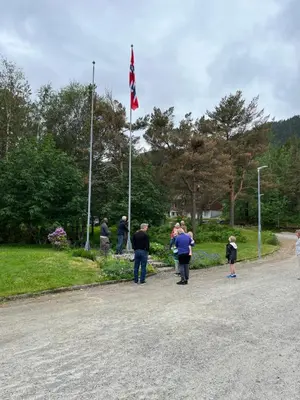 a group of people standing in front of a flag pole at Alværa Misionssenter Sommerhotel in Lavik