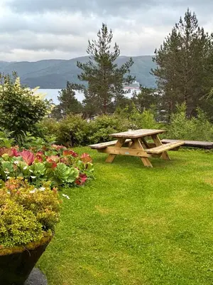 a picnic table in the grass next to some flowers at Alværa Misionssenter Sommerhotel in Lavik
