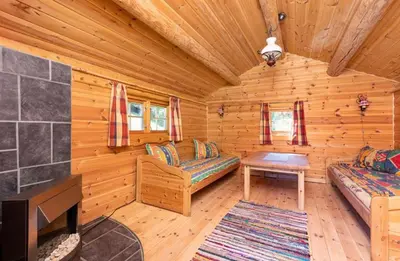 a log cabin living room with a tv and a couch at Skogcamping in Bjørnstad
