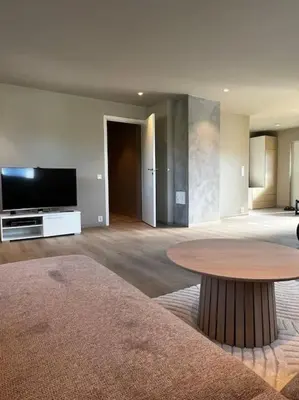 a living room with a table and a flat screen tv at Nyoppusset leilighet midt i sentrum in Verdal