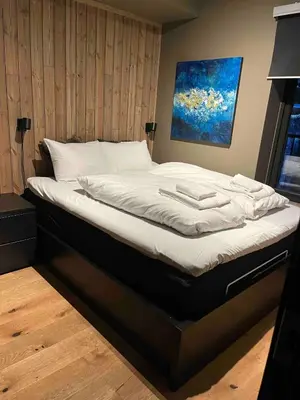 a bed with white sheets and a painting on the wall at Nydelig leilighet på Geilo i Highland fjellandsby in Geilo