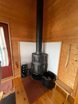 a room with a stove in a wooden cabin at Cozy cabin, minimum 5 nights in Oppheim