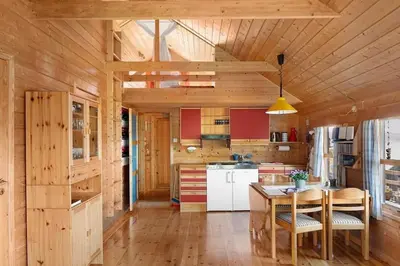 a kitchen with wooden walls and a table and chairs at Cozy cabin, minimum 5 nights in Oppheim
