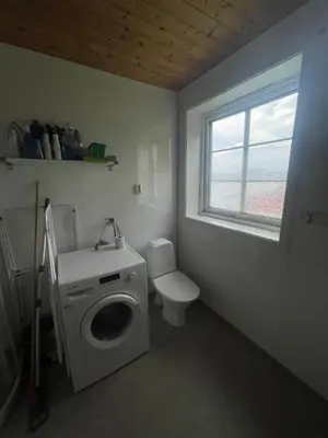 a bathroom with a washing machine and a toilet at Vågen Fjordbuer - Snekkerbua in Ravlo
