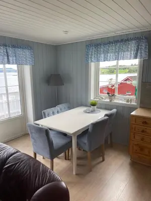 a dining room with a white table and chairs at Vågen Fjordbuer - Snekkerbua in Ravlo