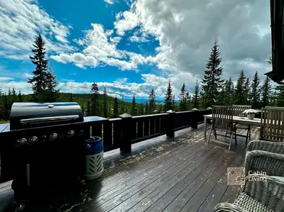 a deck with a grill and a table and chairs at Large log cabin at Sjusjøen with sauna, fireplace and panoramic view in Ringsaker