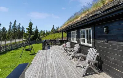 a group of chairs sitting on a deck next to a house at Amazing Home In Sjusjøen With Sauna in Sjusjøen